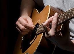 Foto: twee handen bespelen akoestische gitaar